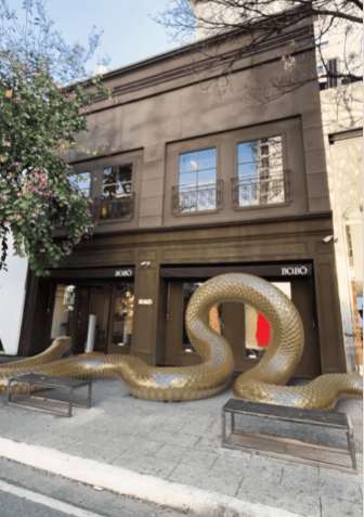Foto da fachada da loja de rua da Bô.Bô em São Paulo, com uma serpente dourada gigante entrando pela porta.